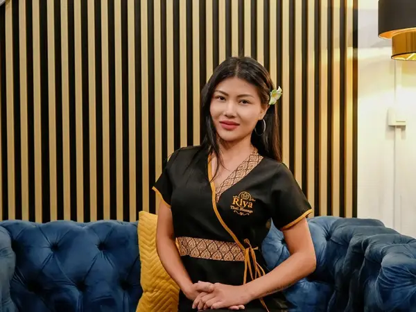 Massage studio interior with striped wall, blue sofa, and smiling staff member
