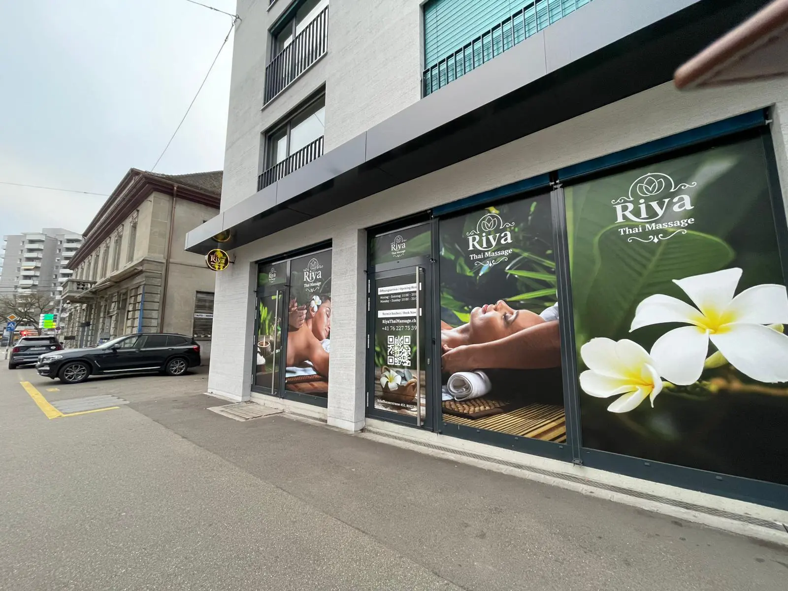 Street-facing Thai massage salon with large floral window graphics in Zürich