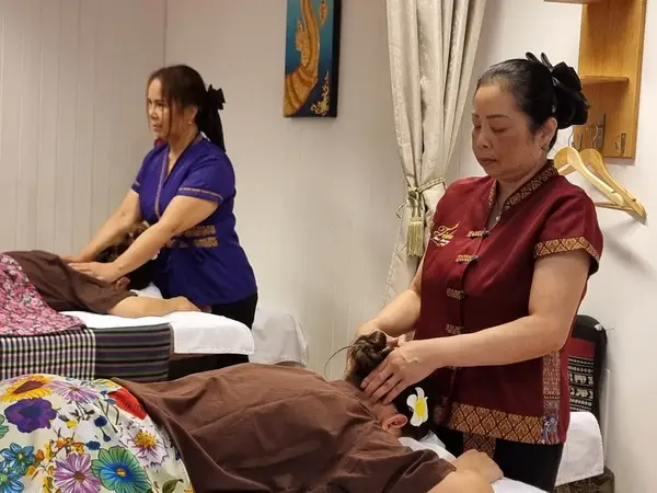 Two therapists massage clients in a calm Thai massage treatment room