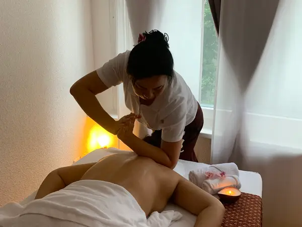 Thai massage room with therapist stretching a client on a table
