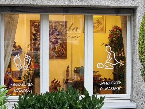 Exterior window of a Thai massage salon with warm yellow interior and wall art