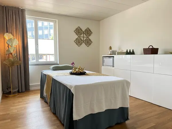 Minimal spa treatment room with massage table, window, and white cabinets