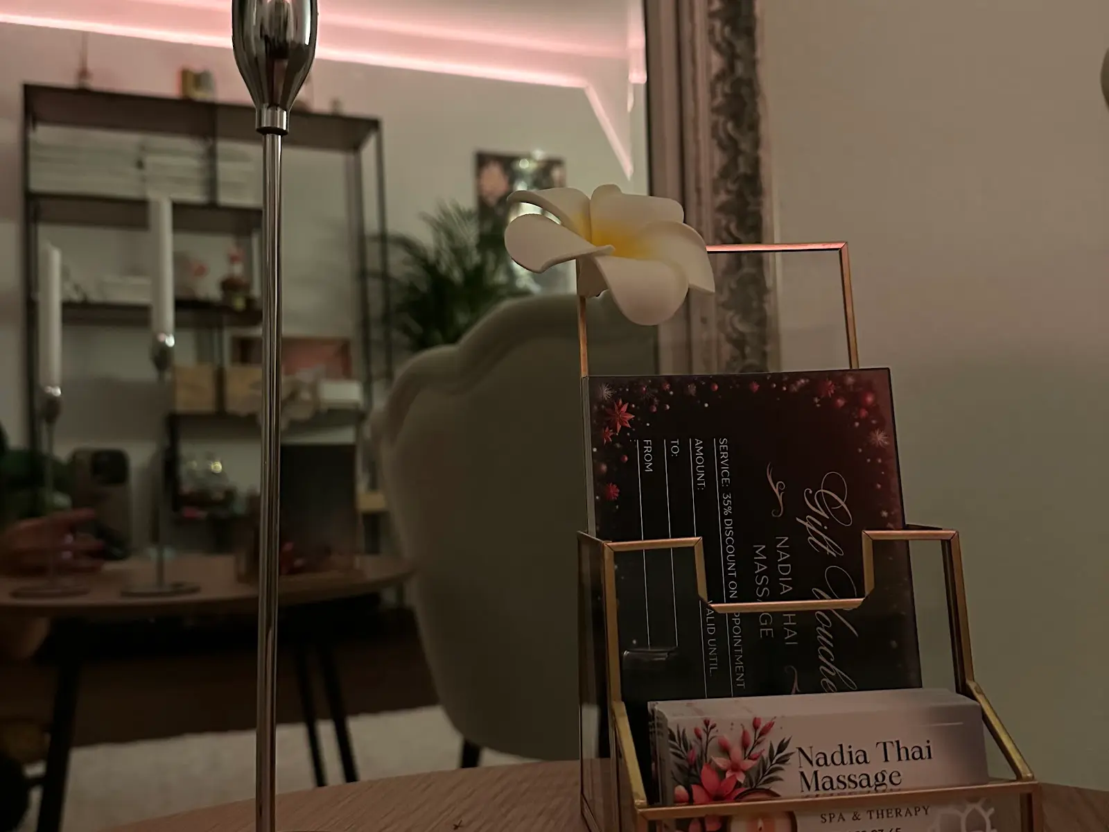 Dim Thai massage reception with desk brochures, mirror, and soft pink lighting