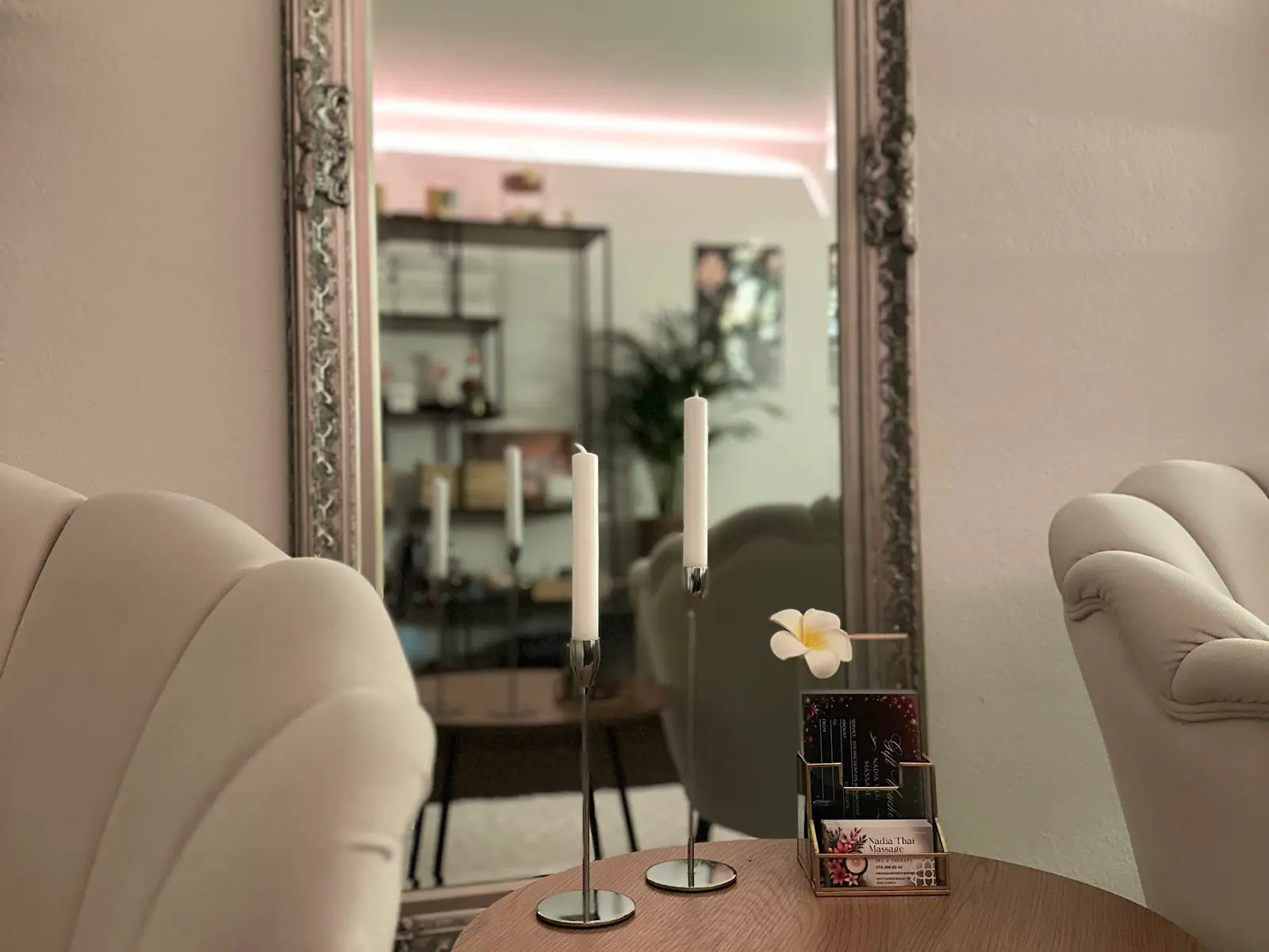 Cozy massage salon seating with candles, mirror, and soft pastel decor