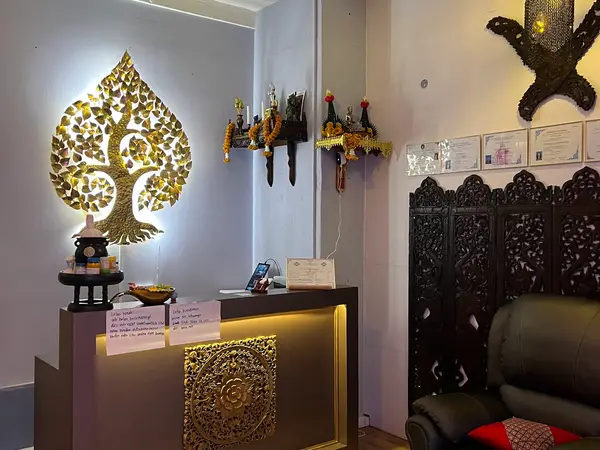 Decorative massage salon reception with ornate wall art and carved wooden screen