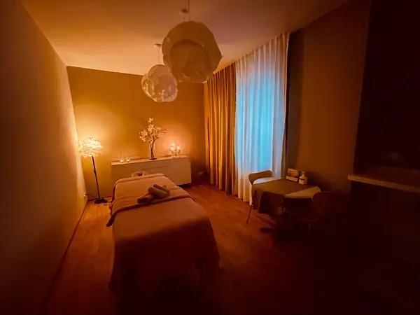 Warm massage room with treatment bed, candles, curtains, and small table