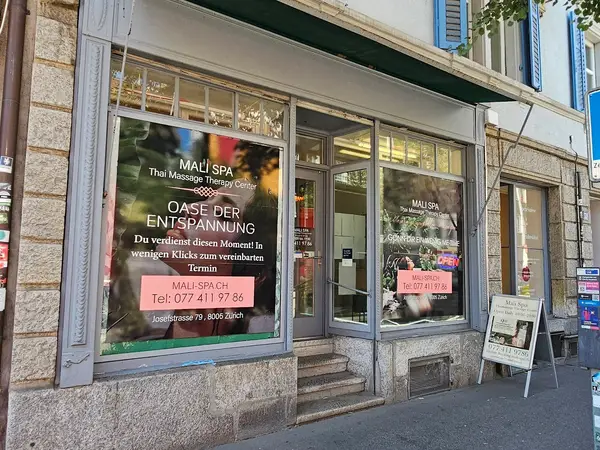 Exterior of a Thai massage salon with large window signs and an open doorway