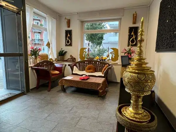 Traditional massage room with Thai decor, wooden seating, and a gold ornament