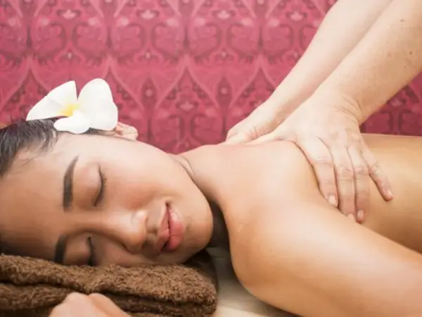 Relaxed woman receiving shoulder massage in a Thai spa room