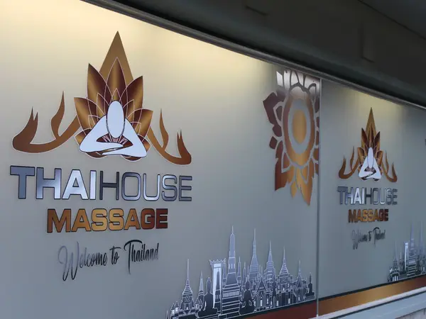Exterior storefront window with Thai House Massage logos and city skyline graphics