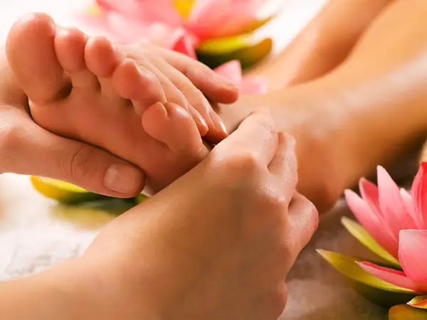 Close-up of foot massage with pink flower decorations and warm lighting