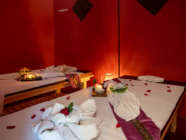 Warm massage room with two decorated treatment beds and red walls