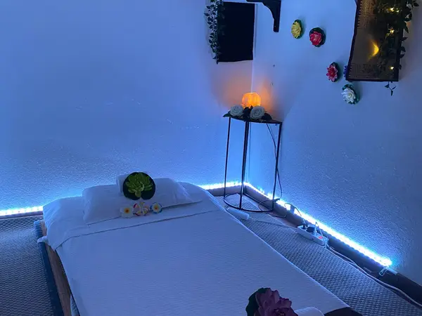 Cozy massage room with bed, glowing lights, and floral wall decor
