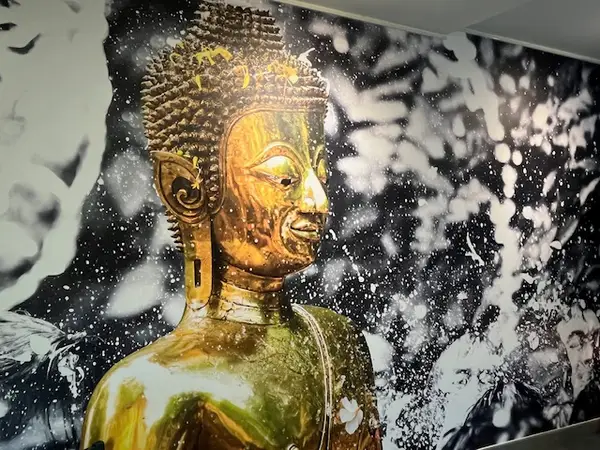 Interior wall mural of a golden Buddha against a black-and-white water backdrop
