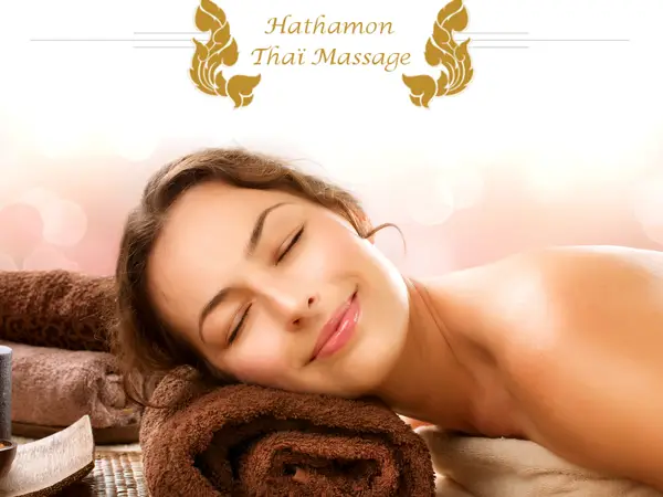 Woman resting on towels in a softly lit massage room with salon logo