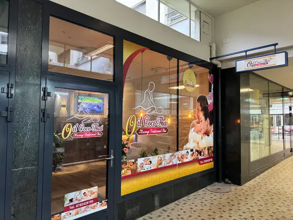 Storefront entrance with large massage-themed window graphics and signage