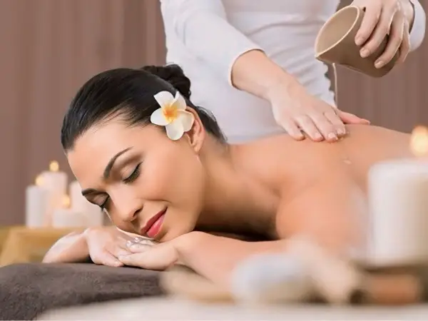 Woman receiving a spa massage with candles and warm beige decor
