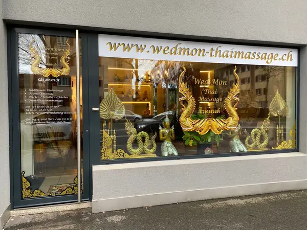 Thai massage storefront with gold window decals and glass door on a street