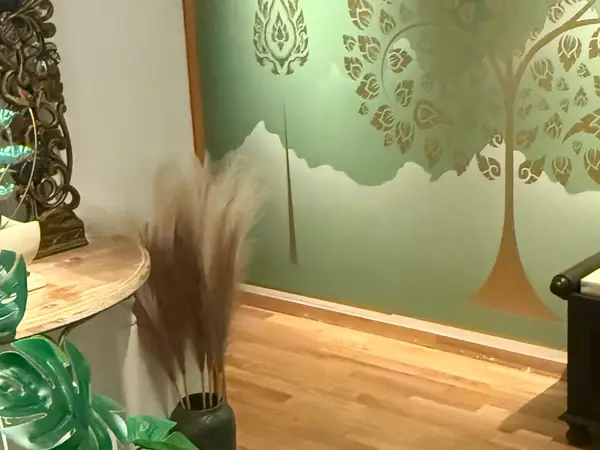 Decorative massage room with wooden floor, green wall art, and plants
