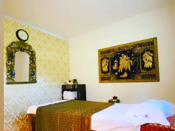 Cozy massage room with ornate wall decor, bed, and warm lighting