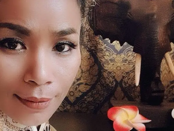 Close-up selfie beside ornate elephant statue and flower decoration