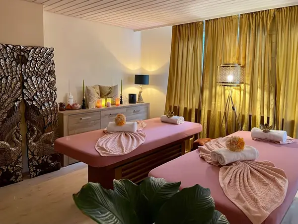 Cozy massage room with pink tables, gold curtains, and decorative wall art