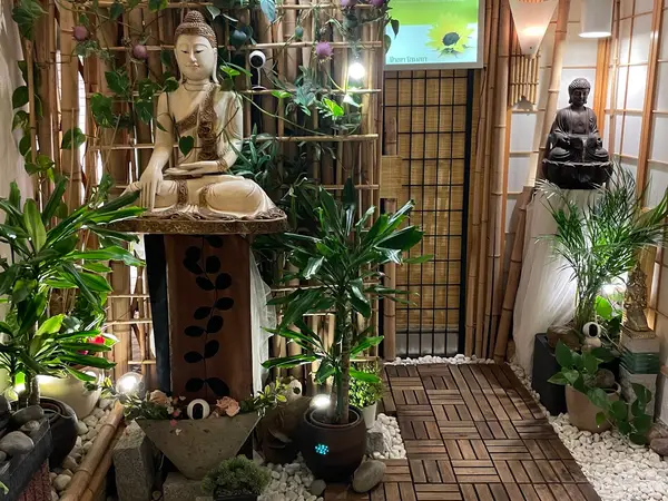 Serene spa entrance with Buddha statues, bamboo decor, and potted plants