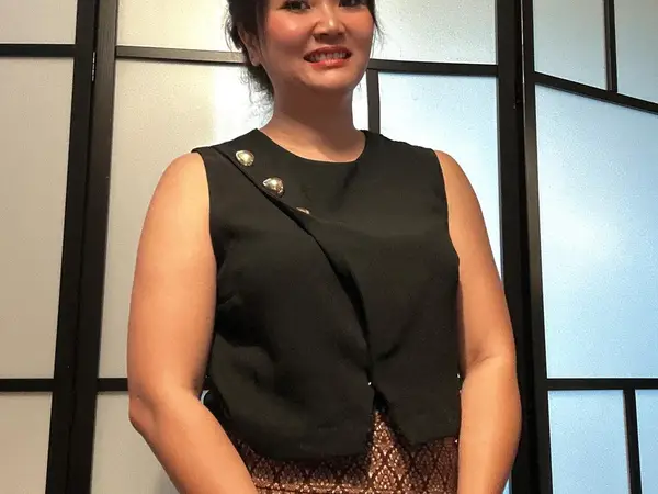 Smiling woman in black uniform stands before a frosted panel screen