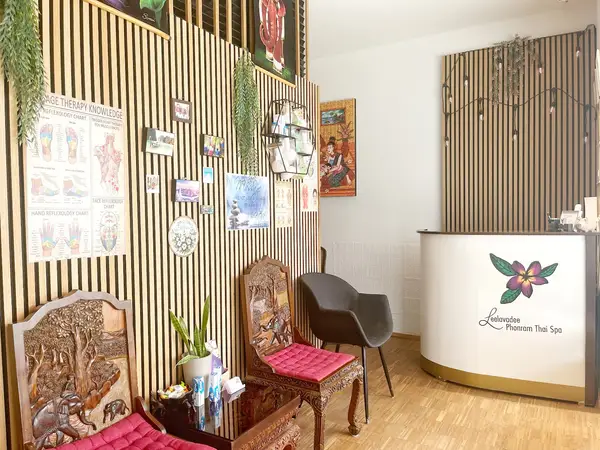 Thai spa reception with carved chairs, striped wood wall, and curved front desk