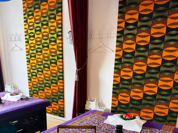 Thai massage treatment room with patterned wall panels and purple-covered tables