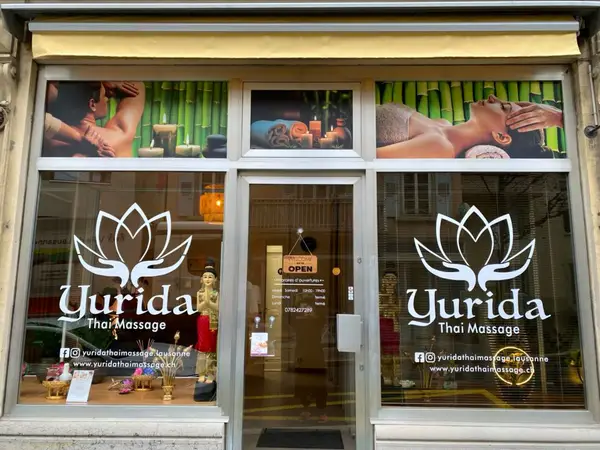 Thai massage salon storefront with large windows, lotus logos, and spa imagery