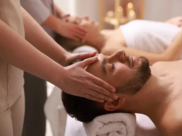 Two massage therapists working on clients in a calm spa treatment room
