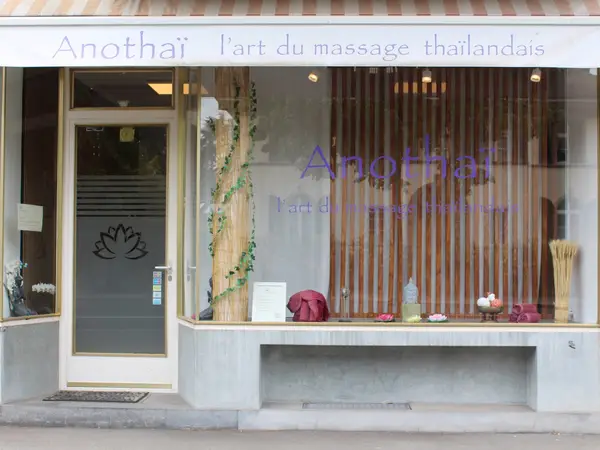 Thai massage salon storefront with large window, frosted door, and wooden slat decor