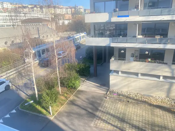 Apartment building exterior beside a street with a tram and parked cars
