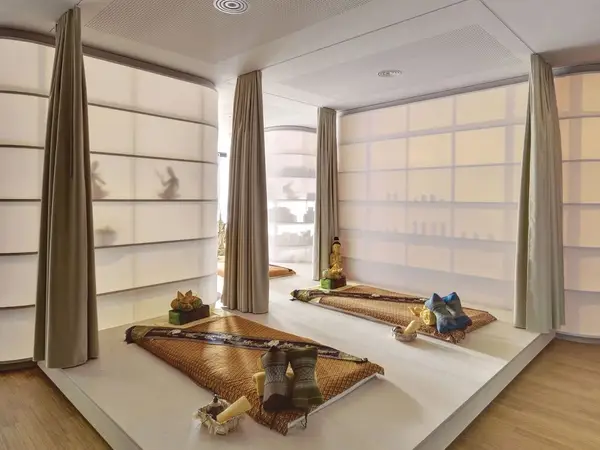 Serene massage room with mats, curtains, and a small Buddha statue