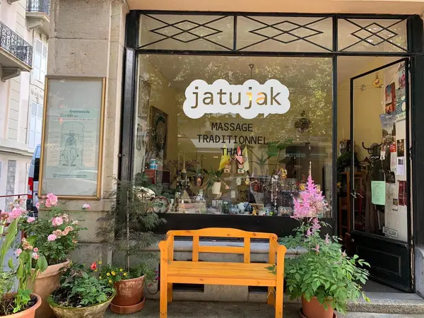 Exterior storefront with orange bench, potted flowers, and Thai massage signage