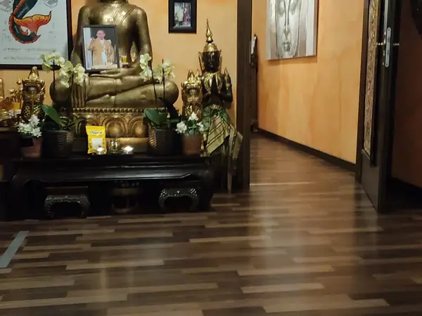 Thai-inspired lobby with golden Buddha statue and dark wood flooring