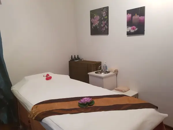 Minimal massage room with a treatment bed, wall art, and candles