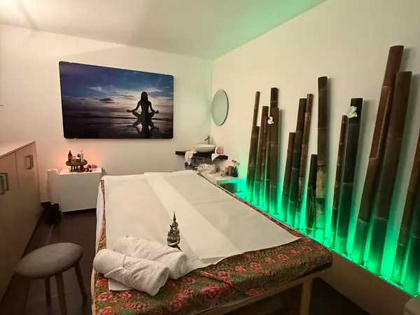 Thai massage treatment room with bamboo decor and green accent lighting