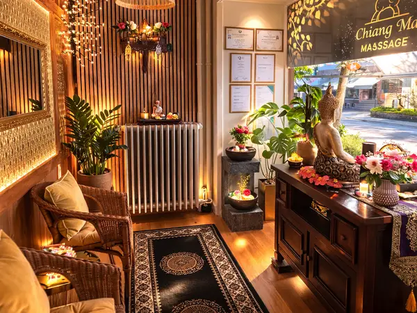 Warm massage salon reception with Thai decor, plants, candles, and Buddha statue