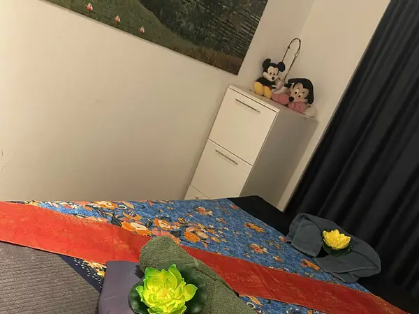 Massage room with colorful bedspread, cabinet, curtains, and stuffed dolls on top