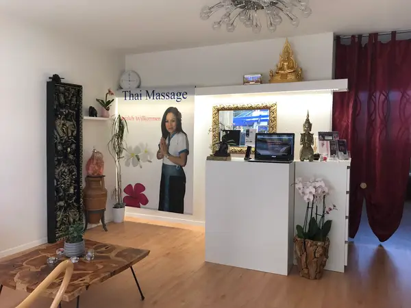Bright Thai massage reception with white counter, decor, and burgundy curtains