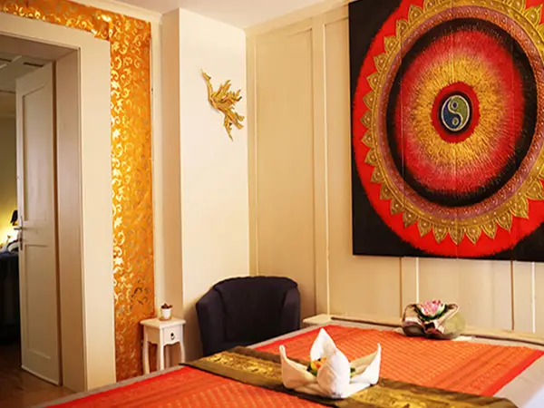 Warm massage room with orange bedspread and large colorful wall art