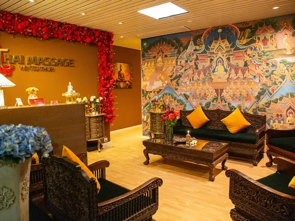 Decorative Thai massage reception with ornate seating and colorful mural wall