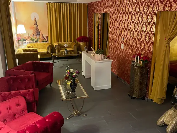 Ornate Thai-style lounge with velvet chairs, gold curtains, and floral decor