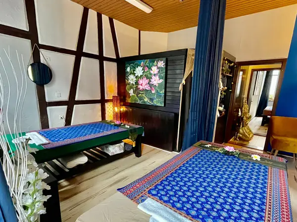 Cozy Thai massage room with two treatment beds, floral decor, and warm lighting