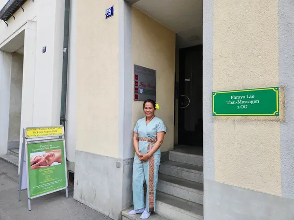 Exterior of Thai massage salon entrance with woman standing by signs