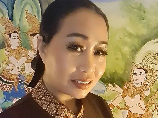 Portrait of a woman in traditional dress before Thai mural art