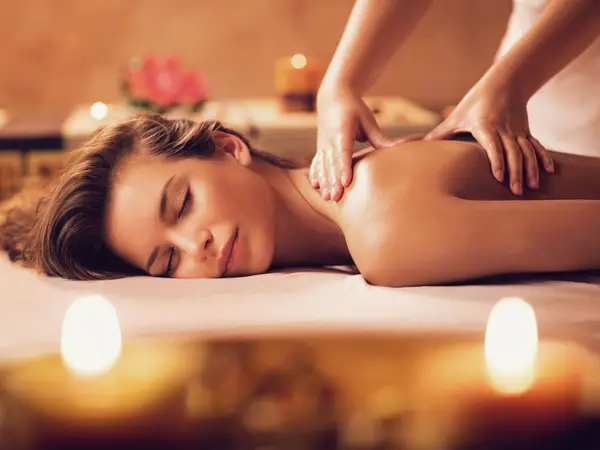 Woman receiving a Thai massage on a cushioned table with candles