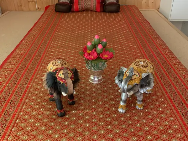 Massage room with red patterned mat, elephant figurines, and flower centerpiece